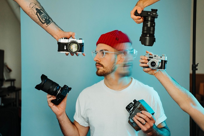 a composite photo of a photographer surrounded by cameras