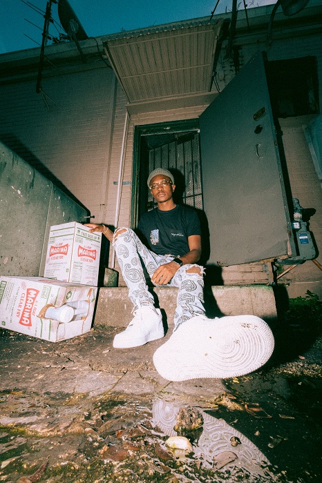 a portrait of a man sitting on a stoop in front of an open door