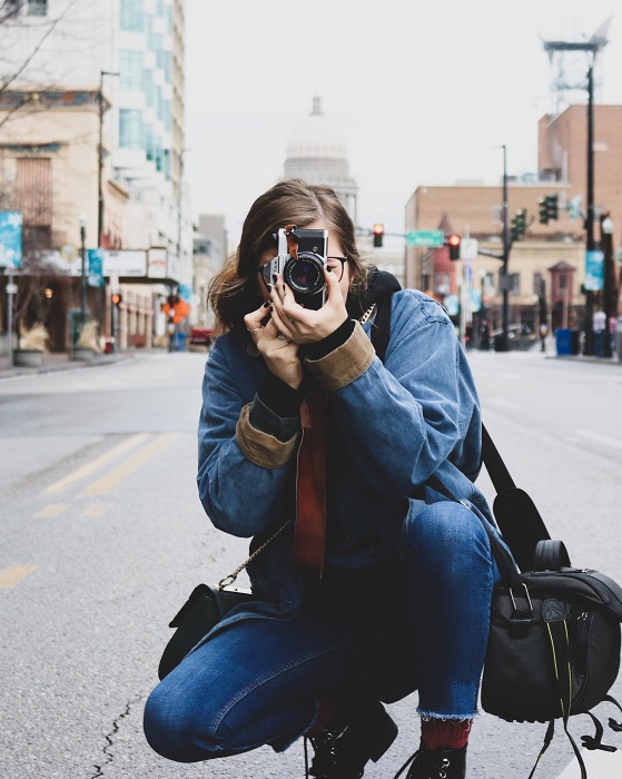 a shot of a photographer shooting a photo in the middle of the road of a busy city