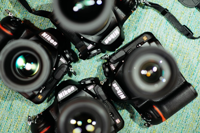 a flat-lay photo of four Nikon DSLRs resting on a teal table