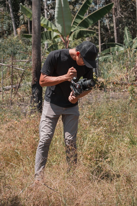 a photographer uses a hybrid camera outdoors in a grass field