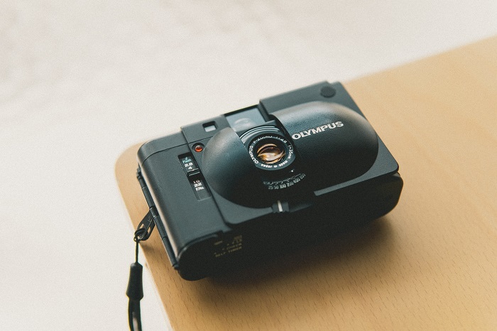 a compact Olympus camera rests on the corner of a desk