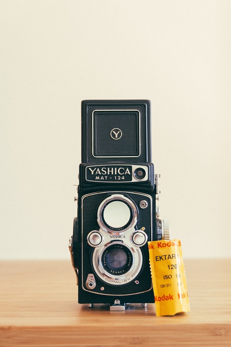 a retro Yashica film camera with Kodak film stock leaning against it