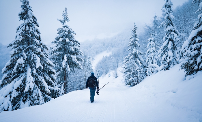 A photographer trekking through a snowy landscape with the bets weather sealed camera