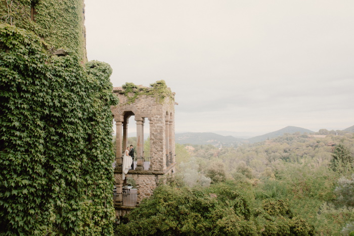 Wedding photo of a couple under a stone gazebo in a Barcelona landscape