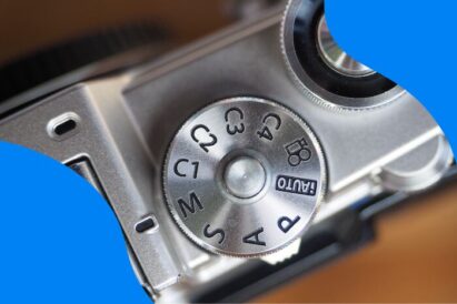 Dial mode and shutter button on silver mirrorless camera.