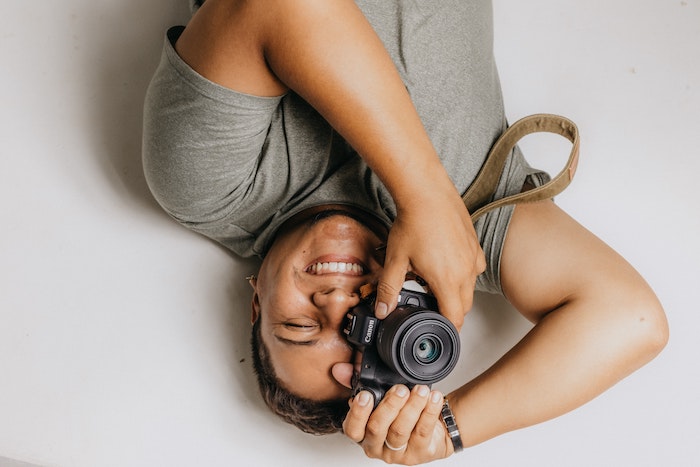 A photographer lying on the ground taking a picture with a Canon camera