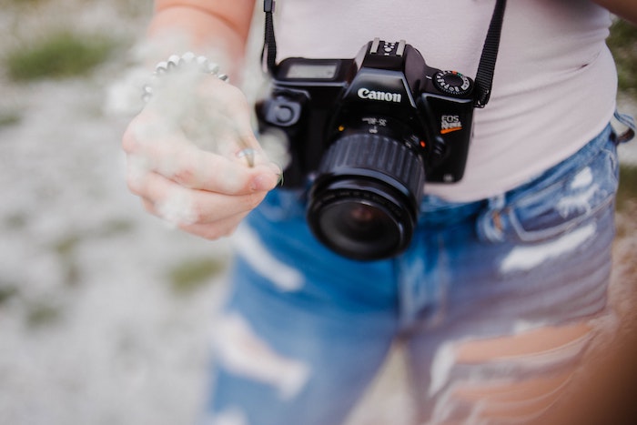 A Canon Rebel DSLR camera hanging off a person's lower body