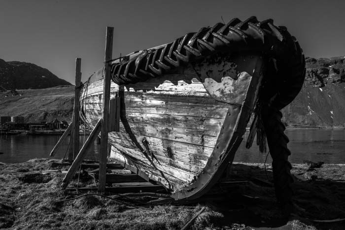 A wooden boat parked up on stilts on a beach in black and white