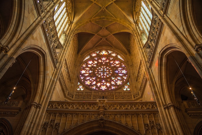 Indoor scene of a church looking up at a stained glass window and arches