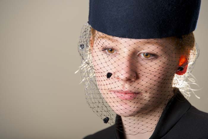 Close-up portrait of a woman wearing a formal hat and veil