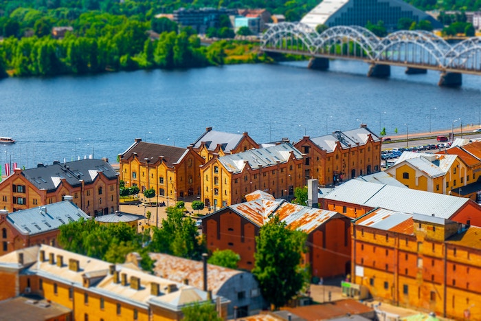 Tilt-shift lens effect on landscape of buildings, trees, and a bridge along a river