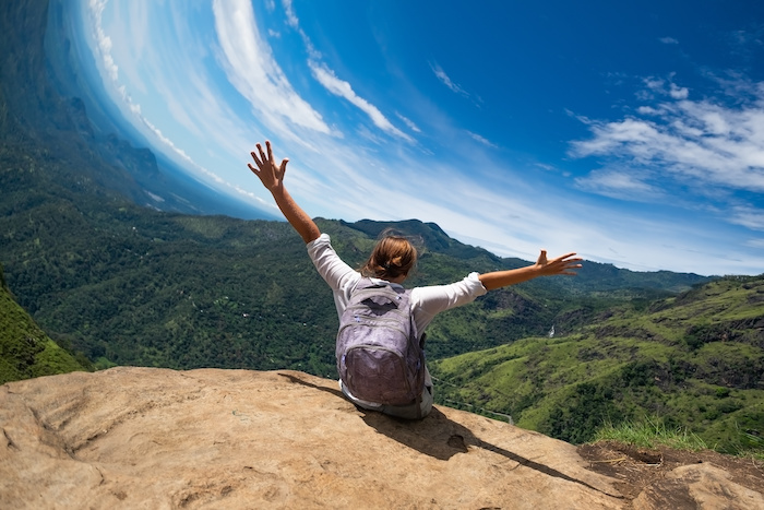 A rolling shutter artifact in the form of a distorted skyline with a hiker sitting on a rock and their arms up in the air