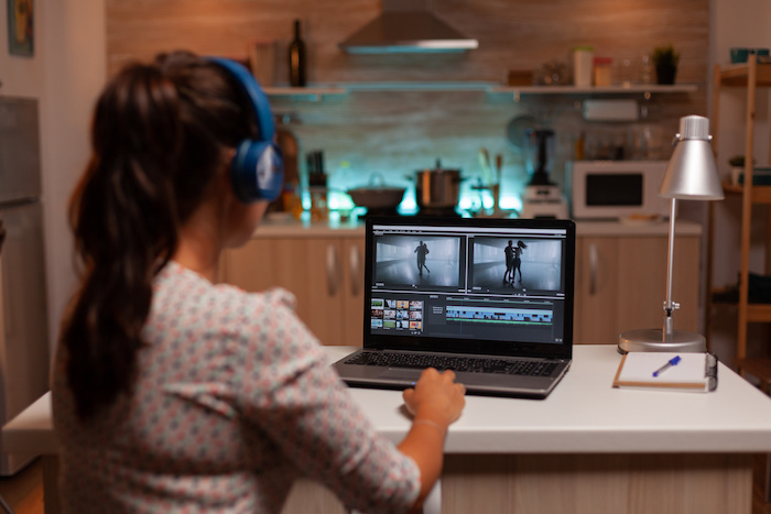 A video editor editing a video on a laptop in her home kitchen