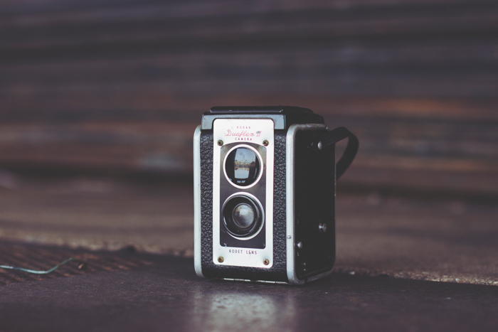  an old film camera against a brown wooden backdrop